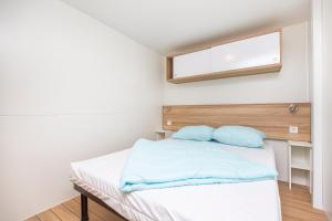 a bedroom with a bed with blue sheets and a window at Albatross Mobile Homes on Camping Cala Canyelles in Lloret de Mar