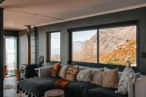 a living room with a couch and large windows at Klein-Hangklip in Rooiels