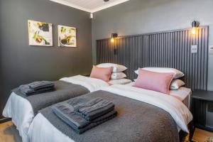 two beds in a bedroom with pink pillows on them at Klein-Hangklip in Rooiels
