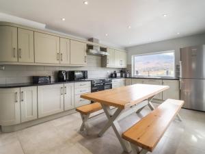 a kitchen with white cabinets and a wooden table at Craig Yr Ronwy in Bala