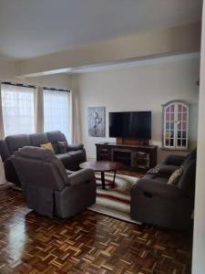 a living room with couches and a flat screen tv at Townhouse Upper Hill Nairobi 2 in Nairobi