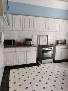 a kitchen with white cabinets and a black and white tile floor at Townhouse Upper Hill Nairobi 2 in Nairobi