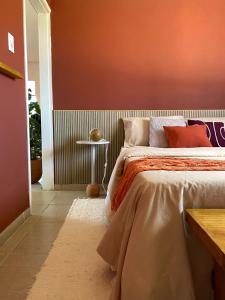 a bedroom with a bed with an orange wall at Casa 90m, dois quartos, próxima às praias in Maceió