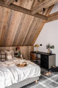 a bedroom with a wooden ceiling with a bed and a desk at Owce Dwie in Zakopane