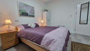a bedroom with a large bed with a purple comforter at Brand New Flat Close To Turnpike Lane Tube Station in London