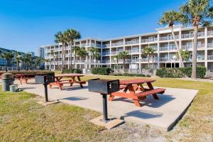 a row of picnic tables in front of a large building at Scenic Views, Hot Tub, Balcony, And Beach Time! in Pensacola
