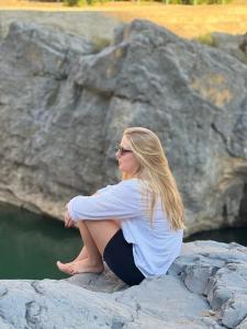 マスカットにあるWadi Al Arbeieen Resortの水辺の岩に腰掛けている女