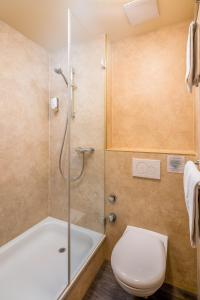 ein Bad mit einer Badewanne, einem WC und einer Dusche in der Unterkunft Alpenrose Hotel and Gardens in Wilderswil