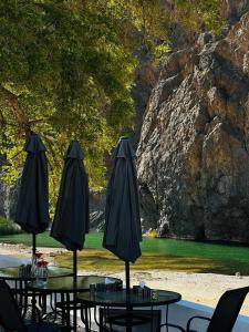 馬斯喀特的住宿－Wadi Al Arbeieen Resort，庭院里一组桌子和遮阳伞