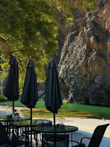 eine Gruppe von Tischen mit Sonnenschirmen auf einer Terrasse in der Unterkunft Wadi Al Arbeieen Resort in Muscat