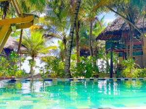 una piscina di fronte a un resort con palme di The Alpha Monkey hotel & Tree house a Tangalle