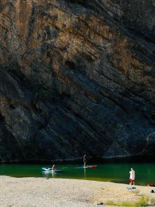 zwei Menschen stehen im Wasser neben einer Felswand in der Unterkunft Wadi Al Arbeieen Resort in Muscat