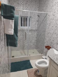 a bathroom with a shower with a toilet and green towels at Majestic Ridge Villas in Soufrière
