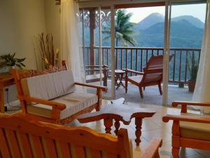a living room with a couch and chairs on a balcony at Majestic Ridge Villas in Soufrière