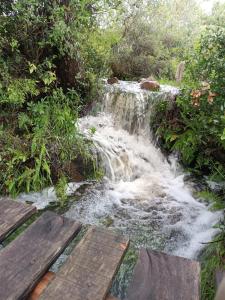 a waterfall with wooden benches in front of a creek at Casa de campo la serena in Minas