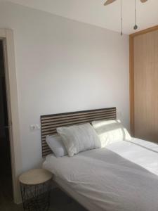 - une chambre avec un lit blanc et une tête de lit en bois dans l'établissement Apart en fuengirola, à Fuengirola