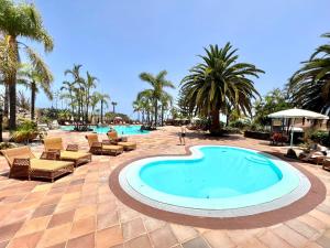 einen Pool in einem Resort mit Stühlen und Palmen in der Unterkunft Apartment AP1, pool, 200 meters to Los Roques Beach in Los Realejos