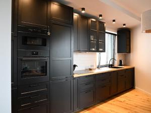 uma grande cozinha com armários e electrodomésticos pretos em APARTAMENT TOPaZ 30 em Konin