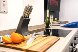 a cutting board with a knife and utensils on a kitchen counter at Luxury City Centre Apartment with Juliet Balcony, Fast Wifi and SmartTV with Netflix by Yoko Property in Aylesbury