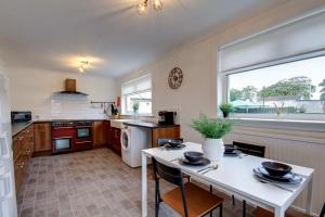 cocina con mesa blanca y ventana en Ravenscroft - Coorie Doon, en Irvine