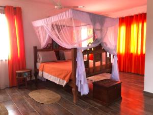 een slaapkamer met een hemelbed en kleurrijke gordijnen bij Emerald Bay Resort in Kizungu
