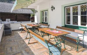 una casa con un patio con mesas y sillas de madera. en Beautiful Apartment In Schladming With 1 Bedrooms And Internet en Gleiming