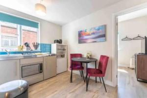 a kitchen with a table and two red chairs at Central Coventry Apartment in Coventry