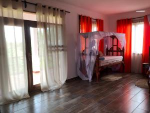 a bedroom with red curtains and a bed with a canopy at Emerald Bay Resort in Kizungu