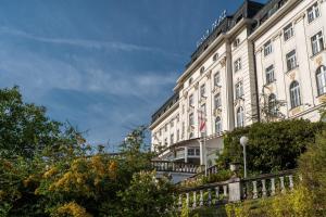 duży biały budynek z płotem przed nim w obiekcie Hotel Radium Palace w mieście Jáchymov