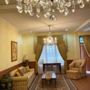a living room with a couch and a chair and a chandelier at Casa Setra Bandung in Bandung