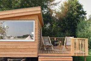 a wooden deck with two chairs and a table at Smûk Tiny nabij het water in Friesland in Echtenerbrug