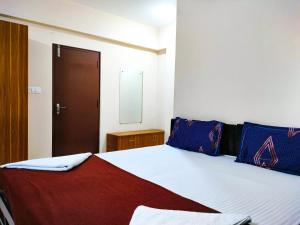 1 dormitorio con 1 cama con almohadas azules y rojas en Primera Extended Stay Apartments, en Bangalore