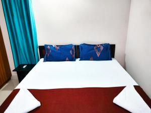 Una cama con dos almohadas azules encima. en Primera Extended Stay Apartments, en Bangalore