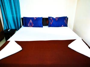 1 cama con almohadas azules en una habitación en Primera Extended Stay Apartments, en Bangalore