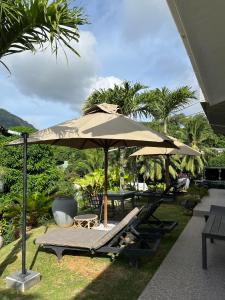 an umbrella and lounge chairs in the grass at 360 Degrees Villa in Victoria