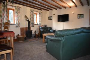 ein Wohnzimmer mit einem grünen Ledersofa und einem Kamin in der Unterkunft The Barn at the Mill in Selattyn