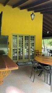 a restaurant with tables and chairs and a yellow wall at Rancho Jatobá in Bonito