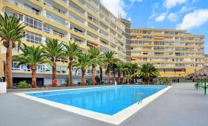 una piscina frente a un edificio con palmeras en vacaciones frente al mar, en Candelaria