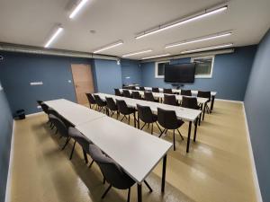 ein Konferenzraum mit Tischen und Stühlen und einem Fernseher in der Unterkunft Apartman 18 in Debrecen