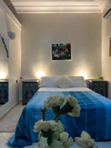 a bedroom with a bed with blue sheets and white flowers at Paradise house in Marrakesh