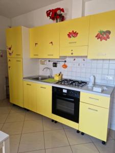 een keuken met gele kasten, een fornuis en een wastafel bij Affitto bilocale Pomezia in Pomezia