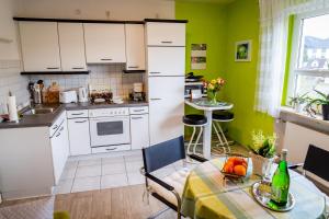 eine Küche mit weißen Geräten und einem Tisch mit einem Esszimmer in der Unterkunft Ferienwohnung Haus am Sommerberg in Ludwigsstadt