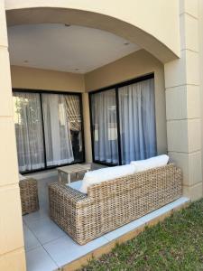 un divano in vimini seduto su una veranda con finestre di Gardens Villa a Nelspruit