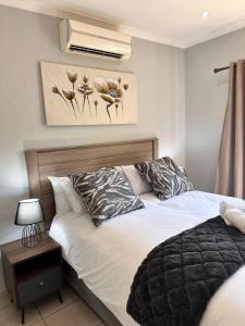 een slaapkamer met een bed en een foto van bloemen bij Gardens Villa in Nelspruit