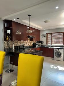 a kitchen with yellow chairs and a counter top at Gardens Villa in Nelspruit