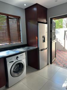 a kitchen with a washing machine and a refrigerator at Gardens Villa in Nelspruit