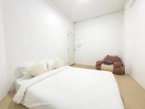 a white bedroom with a large bed and a teddy bear at TRANSIT Donmueang Airport HOSTEL in Thung Si Kan
