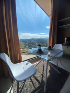 a glass table and chairs in a room with a large window at Chalé Estância da Pinha seu Refúgio na Montanha in Santo Antônio do Pinhal