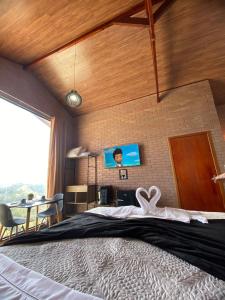 a bedroom with a large bed and a tv on the wall at Chalé Estância da Pinha seu Refúgio na Montanha in Santo Antônio do Pinhal