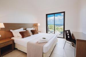 a bedroom with a bed with a desk and a window at Résidence Les Terrasses de Rondinara in Bonifacio